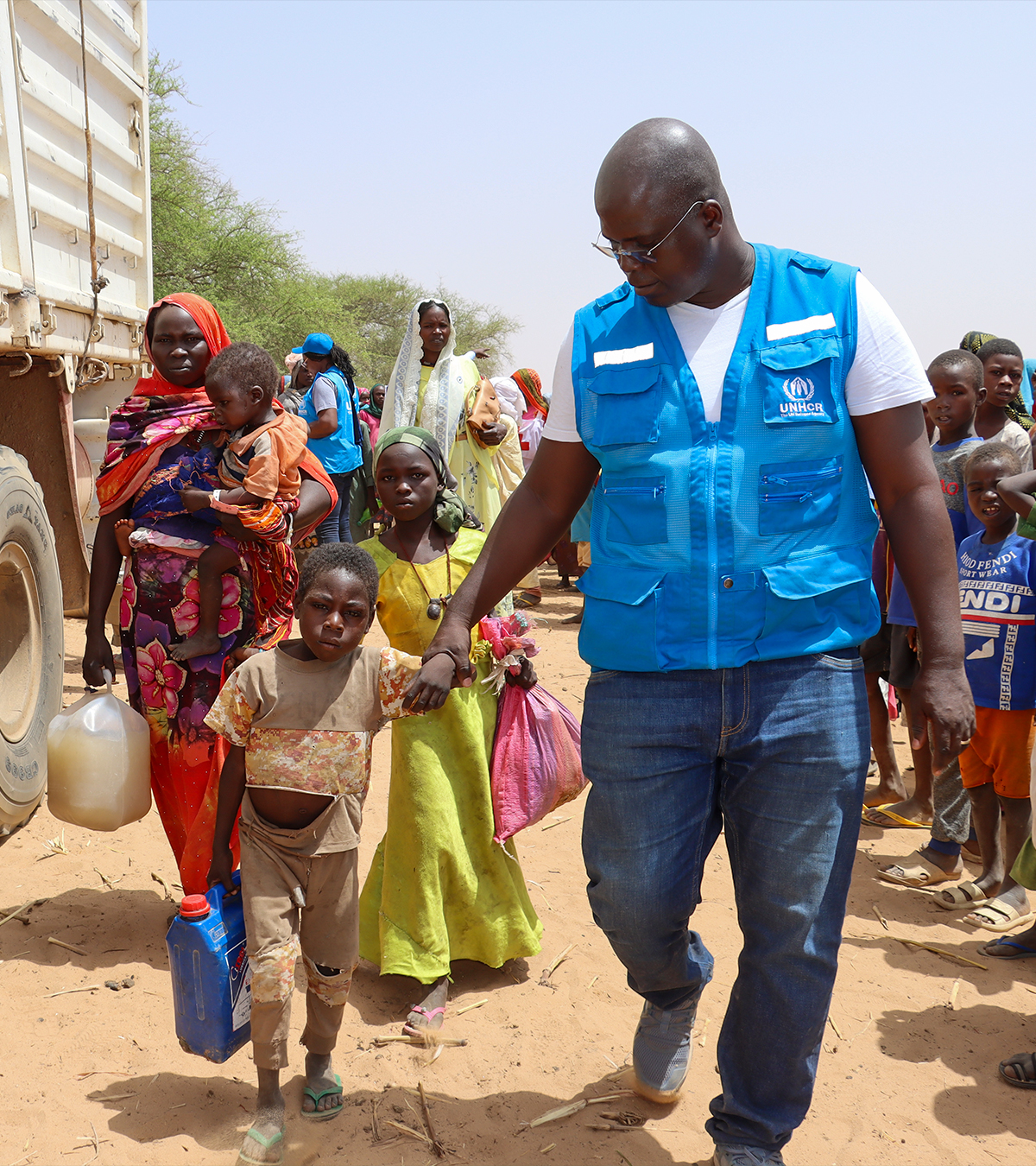 Funcionário do ACNUR ajuda criança refugiada.